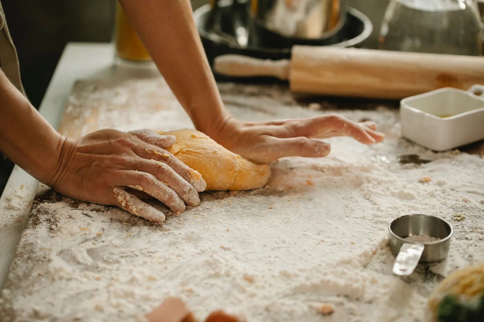 Baker kneading fresh dough on a floured wooden surface
